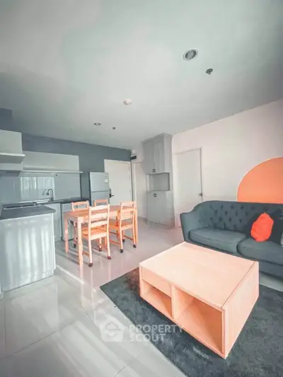 Modern open-plan living room with stylish furniture and sleek kitchen area.