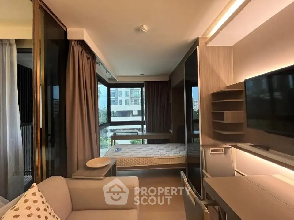 Modern studio apartment with large windows and stylish furnishings, offering a bright and inviting living space.