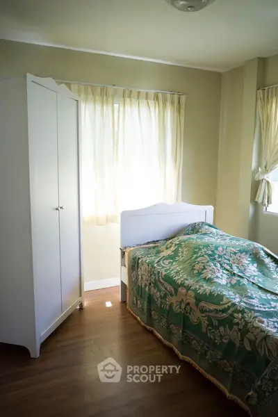 Cozy bedroom with natural light, featuring a single bed and wardrobe, perfect for a serene retreat.