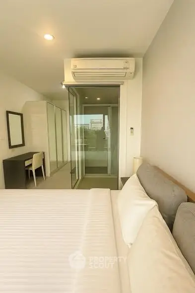 Modern bedroom with air conditioning and sliding glass doors to balcony