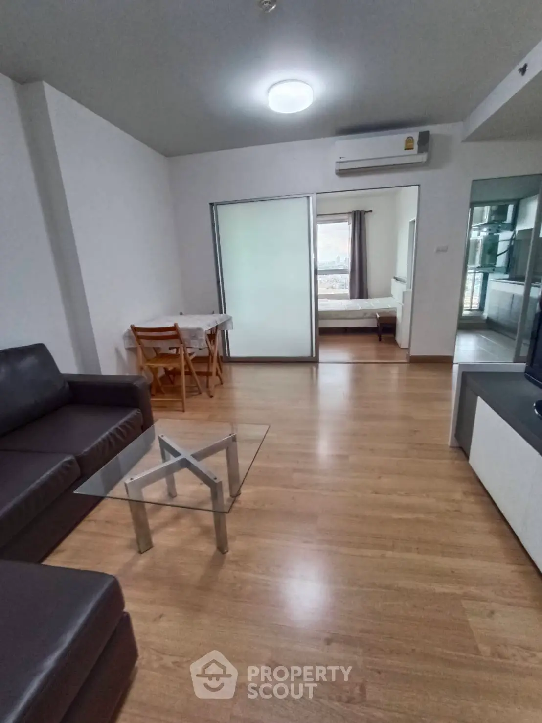 Modern living room with glass coffee table and sliding doors leading to bedroom