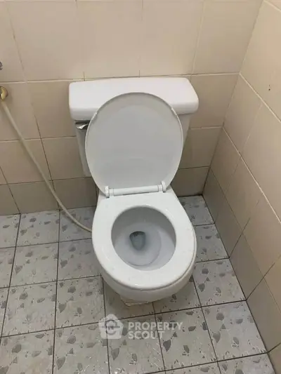 Compact bathroom with standard toilet and tiled flooring, ideal for efficient space utilization.