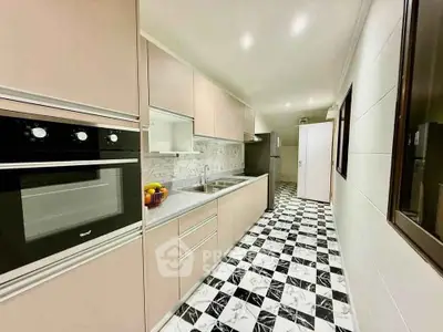 Modern kitchen with sleek cabinetry, built-in oven, and stylish checkered flooring.