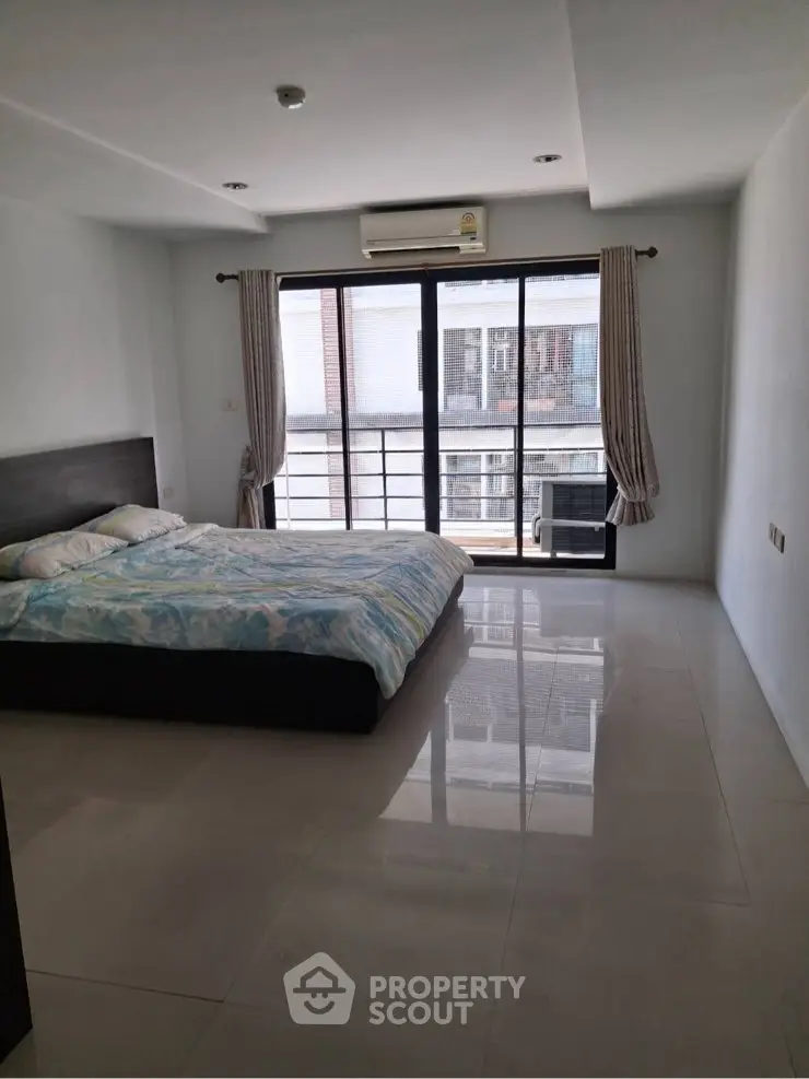 Spacious bedroom with large window and modern decor in urban apartment