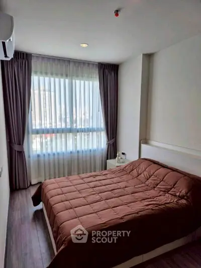 Cozy bedroom with large window and modern decor in urban apartment.