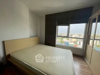 Spacious bedroom with large window offering stunning city views, perfect for urban living.