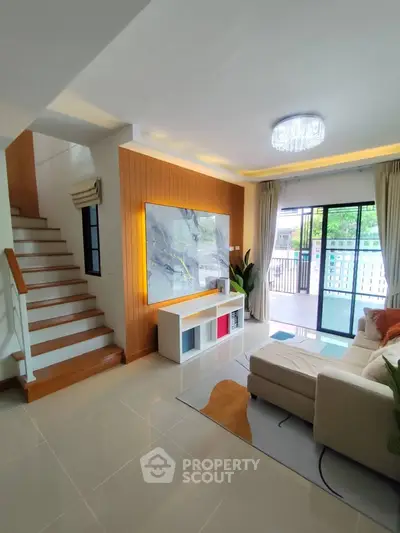 Modern living room with stylish decor and natural light, featuring a cozy sofa and elegant staircase.