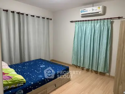 Cozy bedroom with wooden flooring and air conditioning, featuring a bed with starry bedding and elegant curtains.