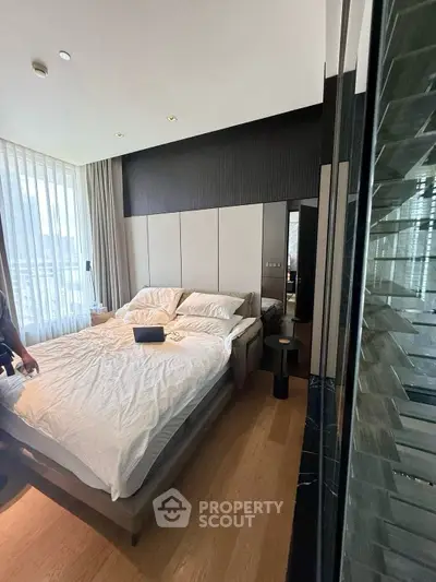 Luxurious bedroom with modern decor and large windows offering natural light and city views.