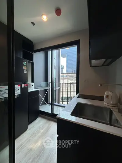 Modern kitchen with sleek black cabinets and balcony view in urban apartment
