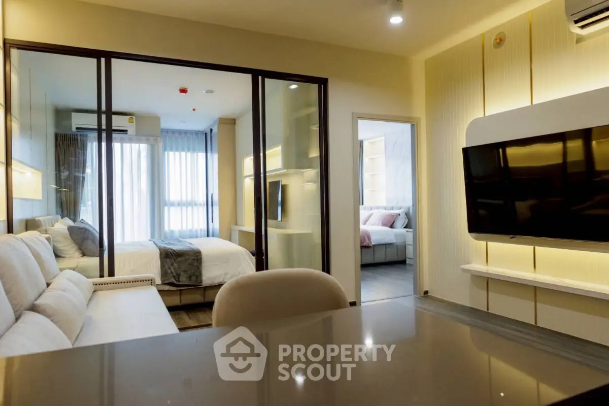 Modern apartment interior with open living room and bedroom, featuring sleek design and ample natural light.