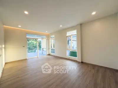 Spacious empty living room with large windows and wooden flooring