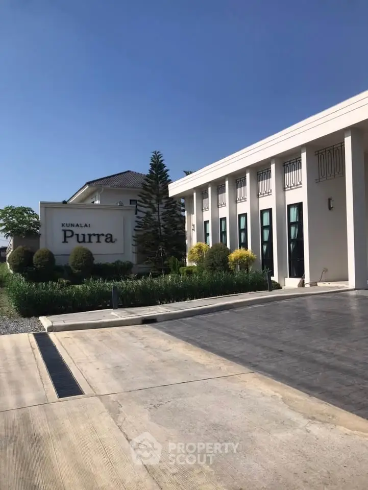 Modern residential building with elegant facade and lush landscaping under clear blue sky.