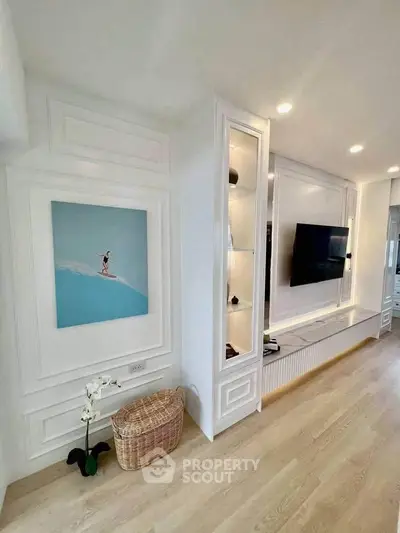 Modern living room with elegant wall paneling and mounted TV, featuring light wood flooring and stylish decor.