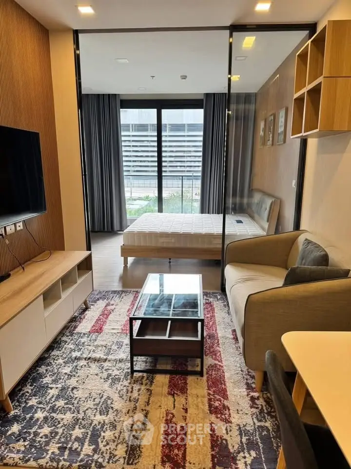 Modern studio apartment with stylish living area and bedroom, featuring glass partition and contemporary decor.
