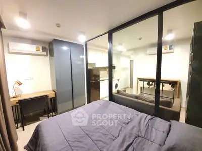 Modern studio apartment with glass partition, cozy bedroom, and compact kitchen.