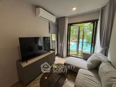Cozy living room with modern decor and pool view through large window.