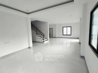 Spacious modern living room with sleek staircase and large windows