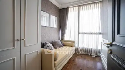 Charming small living area with elegant sofa and large window, perfect for cozy relaxation.