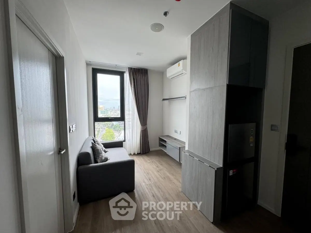 Modern living room with city view, featuring sleek furniture and natural light.
