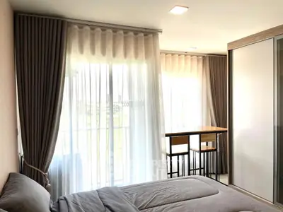 Modern bedroom with large windows and stylish curtains, featuring a cozy bed and sleek furniture.