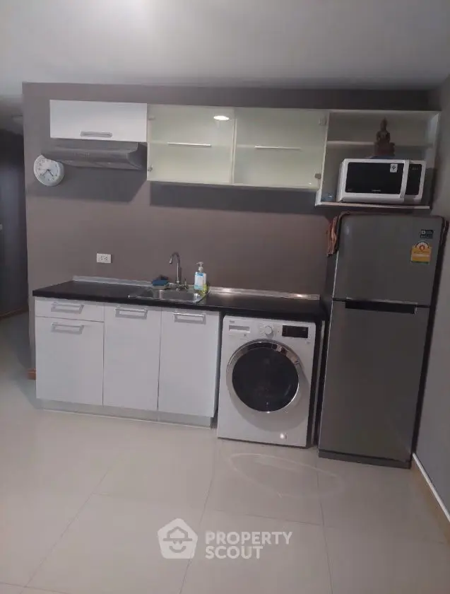 Modern compact kitchen with washing machine and fridge, ideal for urban living.