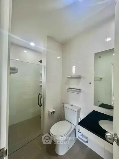 Modern bathroom with glass shower and sleek fixtures in a contemporary apartment.