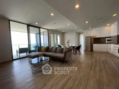Spacious modern living room with open kitchen and large balcony offering stunning ocean views.