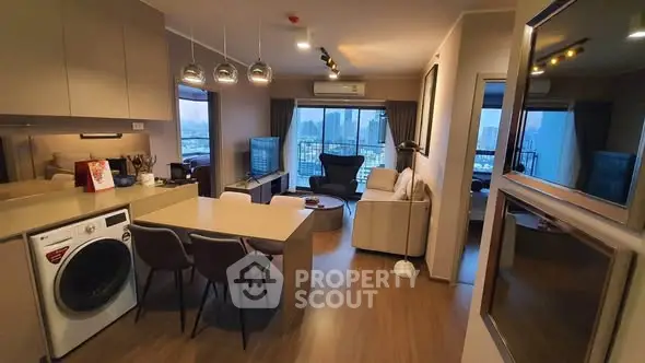 Modern open-layout living room with city view, featuring stylish furniture and integrated kitchen appliances.