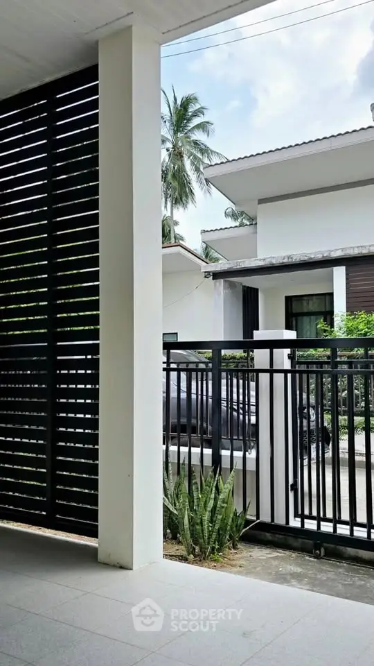 Modern house exterior with sleek fence and lush greenery