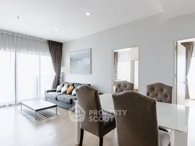 Modern living room with elegant dining area and large windows for natural light.
