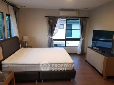 Spacious bedroom with large windows and modern furnishings in a stylish home.