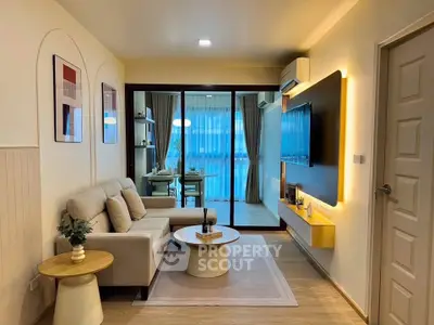 Modern living room with cozy seating and stylish decor, featuring a view into a bright dining area.