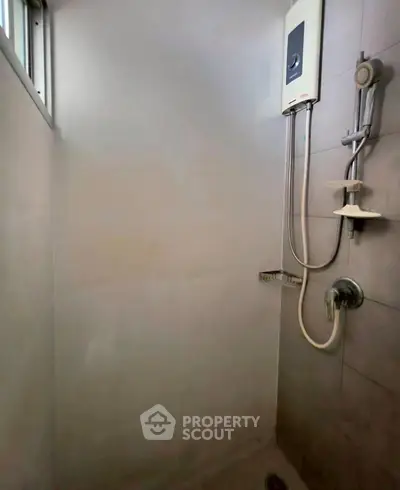 Modern bathroom shower area with sleek fixtures and water heater.