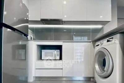 Modern kitchen with sleek appliances including fridge, microwave, and washing machine.