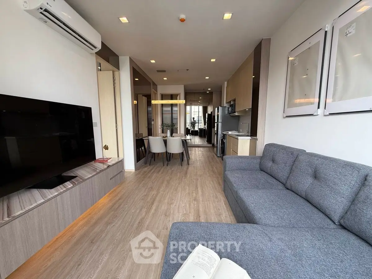 Modern living room with open layout, stylish furniture, and sleek kitchen design.