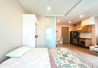 Modern studio apartment with open layout, featuring a cozy bed and compact kitchen area.