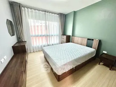 Spacious bedroom with modern furniture and large window for natural light.