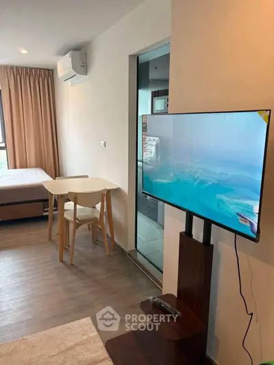 Modern studio apartment with sleek TV setup and cozy dining area.