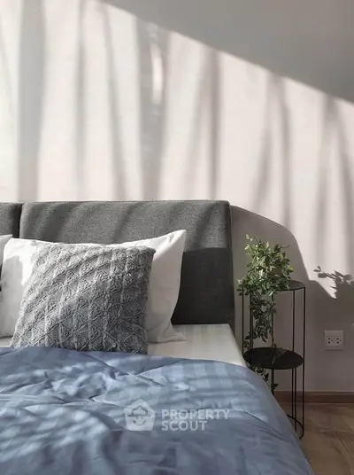 Cozy bedroom with stylish decor and natural light, featuring a plush bed and elegant side table.