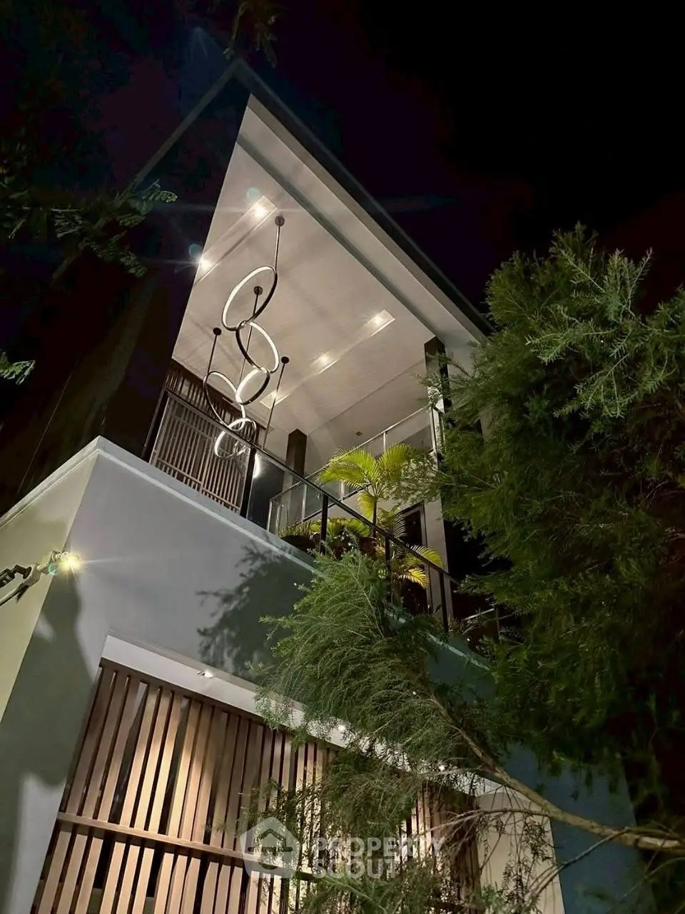 Stunning modern home exterior with elegant lighting and lush greenery at night.