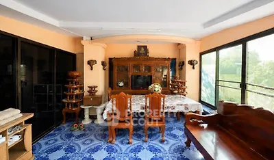 Charming dining area with traditional wooden furniture and large windows offering lush garden views.