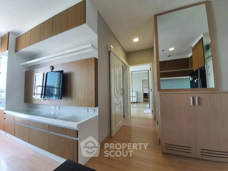 Modern living room with sleek wooden cabinetry and mounted TV, showcasing contemporary interior design.