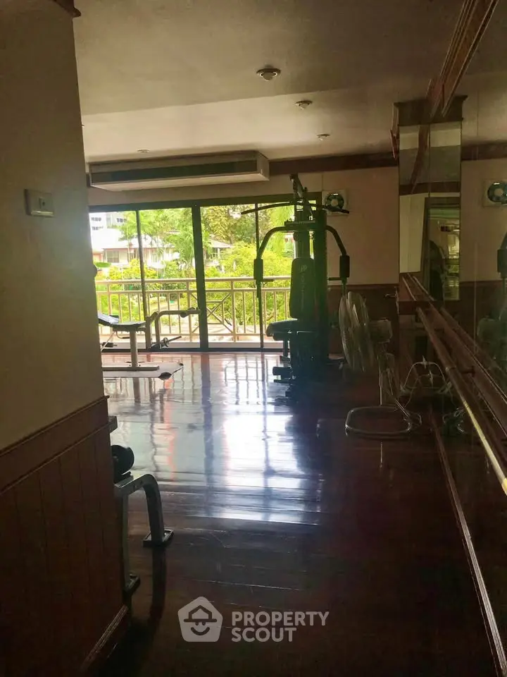 Spacious gym with modern equipment and large windows offering a scenic view, perfect for fitness enthusiasts.