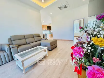 Spacious living room with modern sofa and elegant decor, open layout leading to a stylish kitchen.