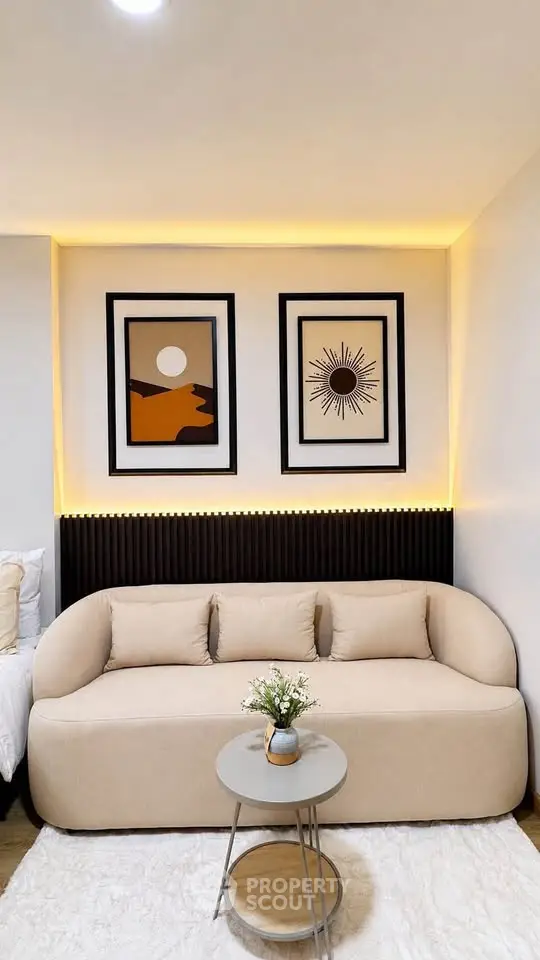 Modern living room with stylish beige sofa, artistic wall decor, and cozy lighting.