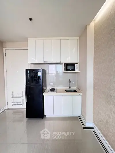 Modern compact kitchen with sleek cabinetry and appliances in a stylish apartment.