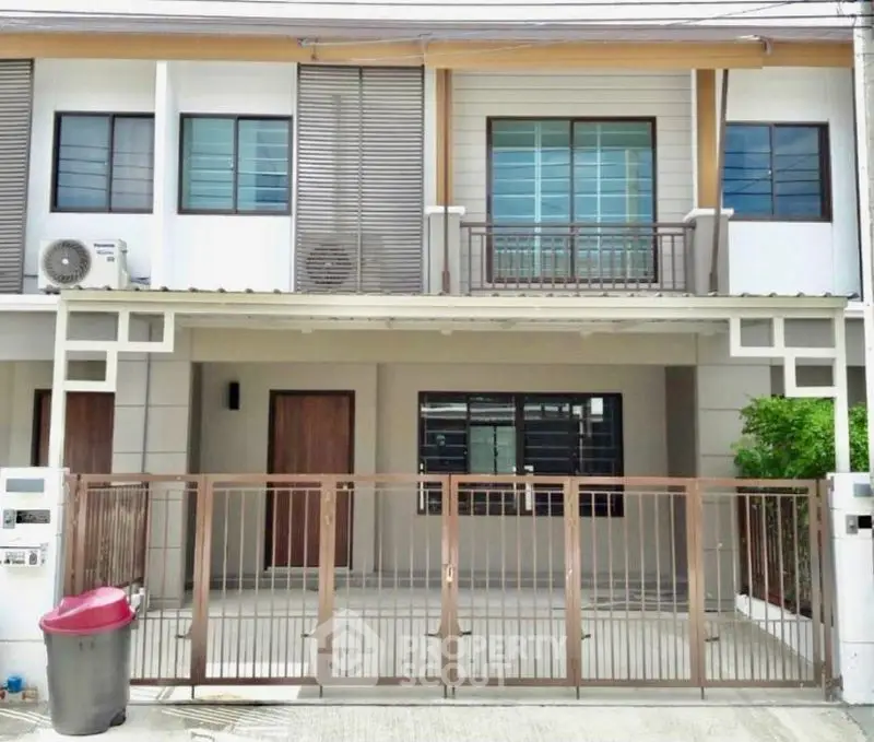 Modern townhouse exterior with gated entrance and balcony.
