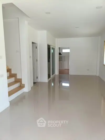 Spacious open-plan living area with glossy floors and modern staircase