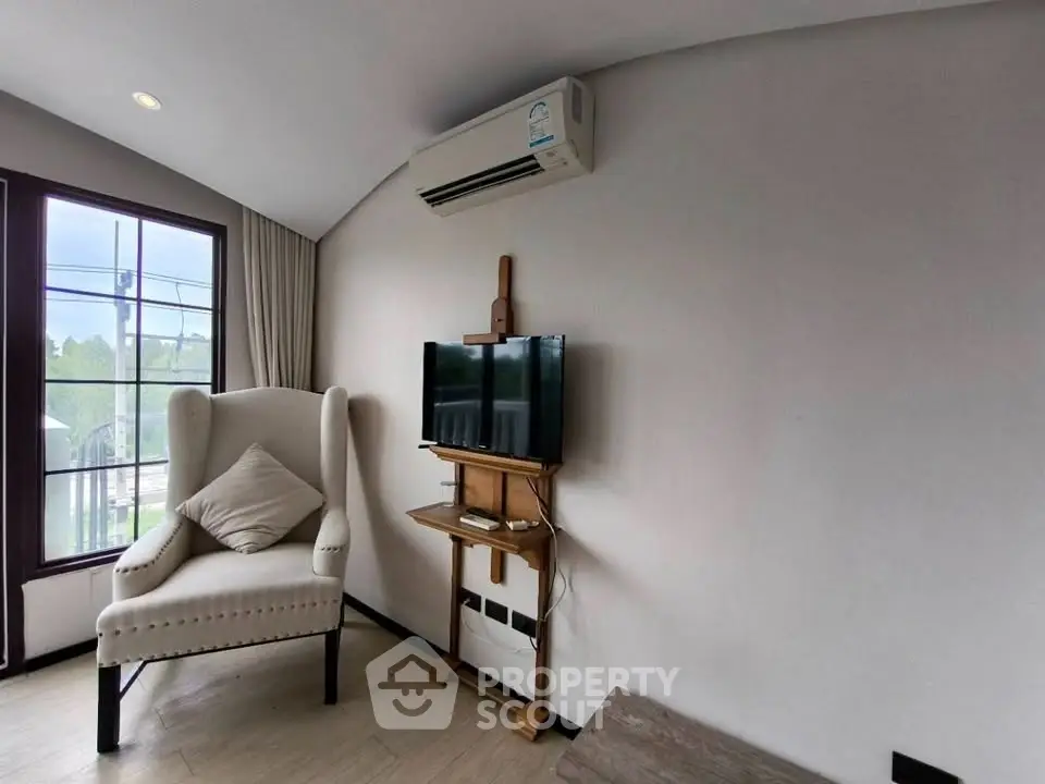 Cozy living room with armchair, wall-mounted TV, and air conditioning unit.